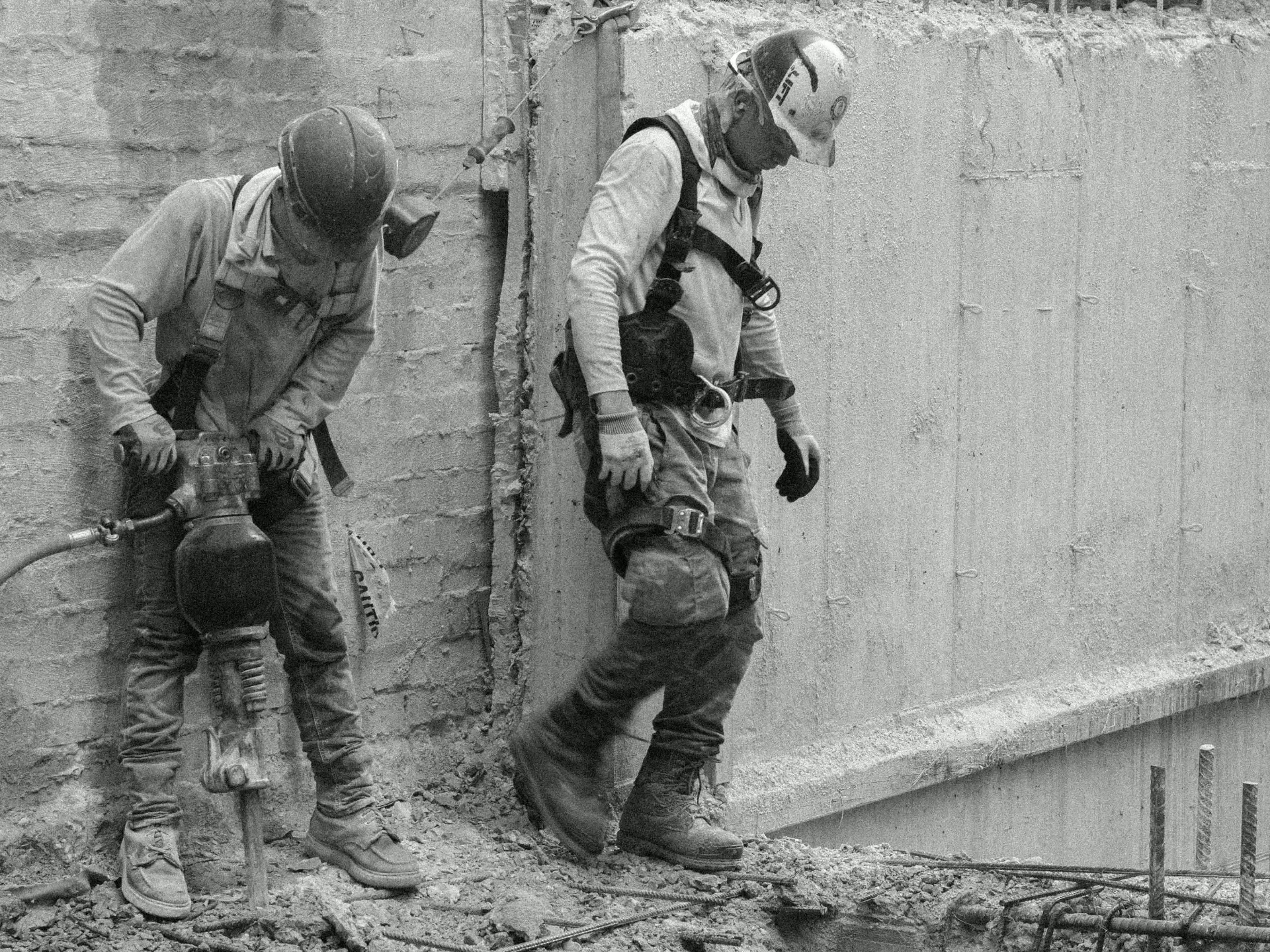 Ironworkers carrying rebar across an active foundation site