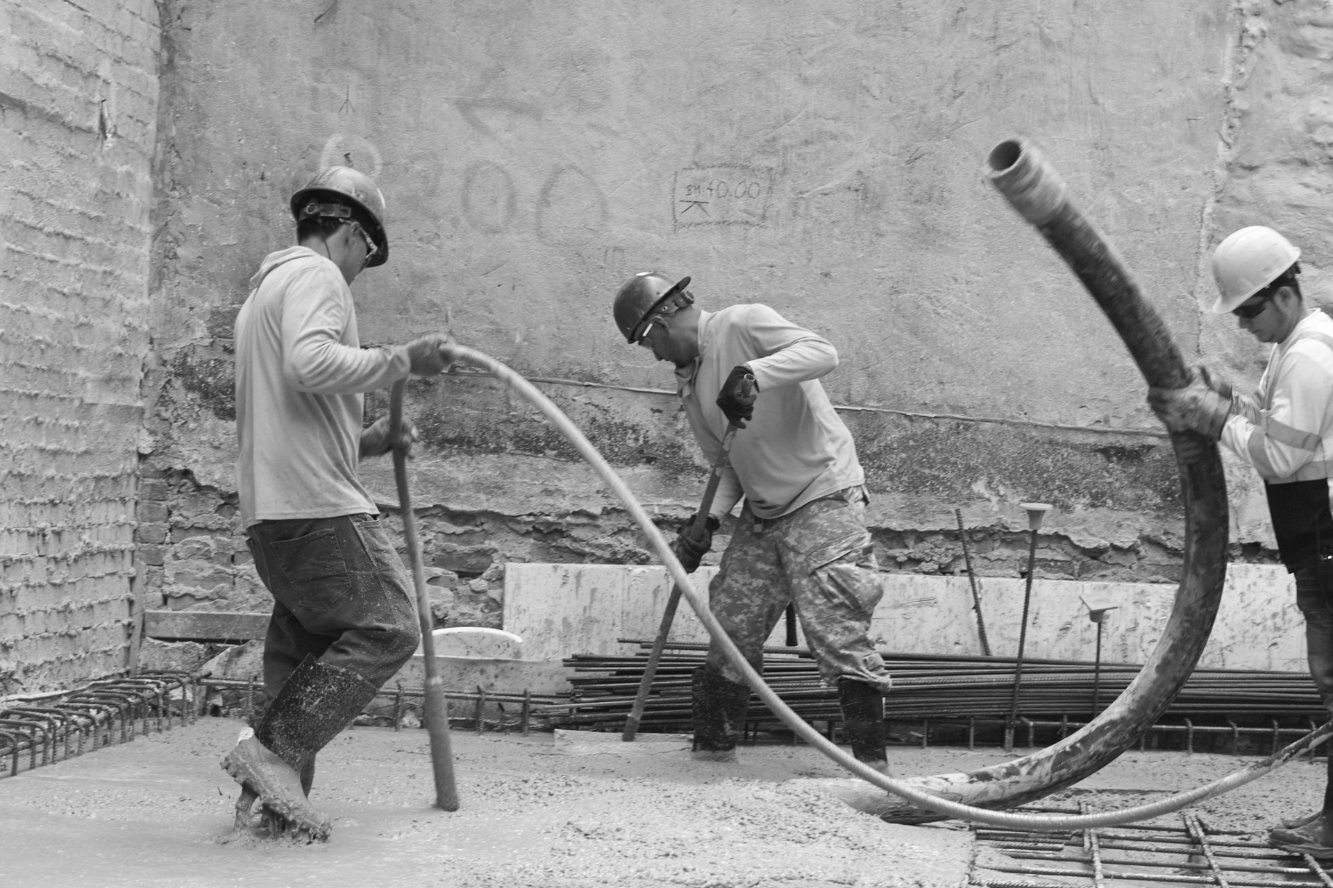 Workers placing concrete with a pump hose on a fresh slab